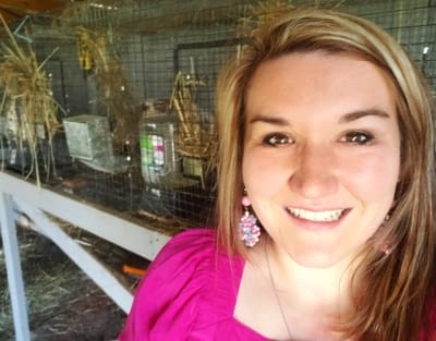 Picture of Laura Pierce with rabbit cages in background.